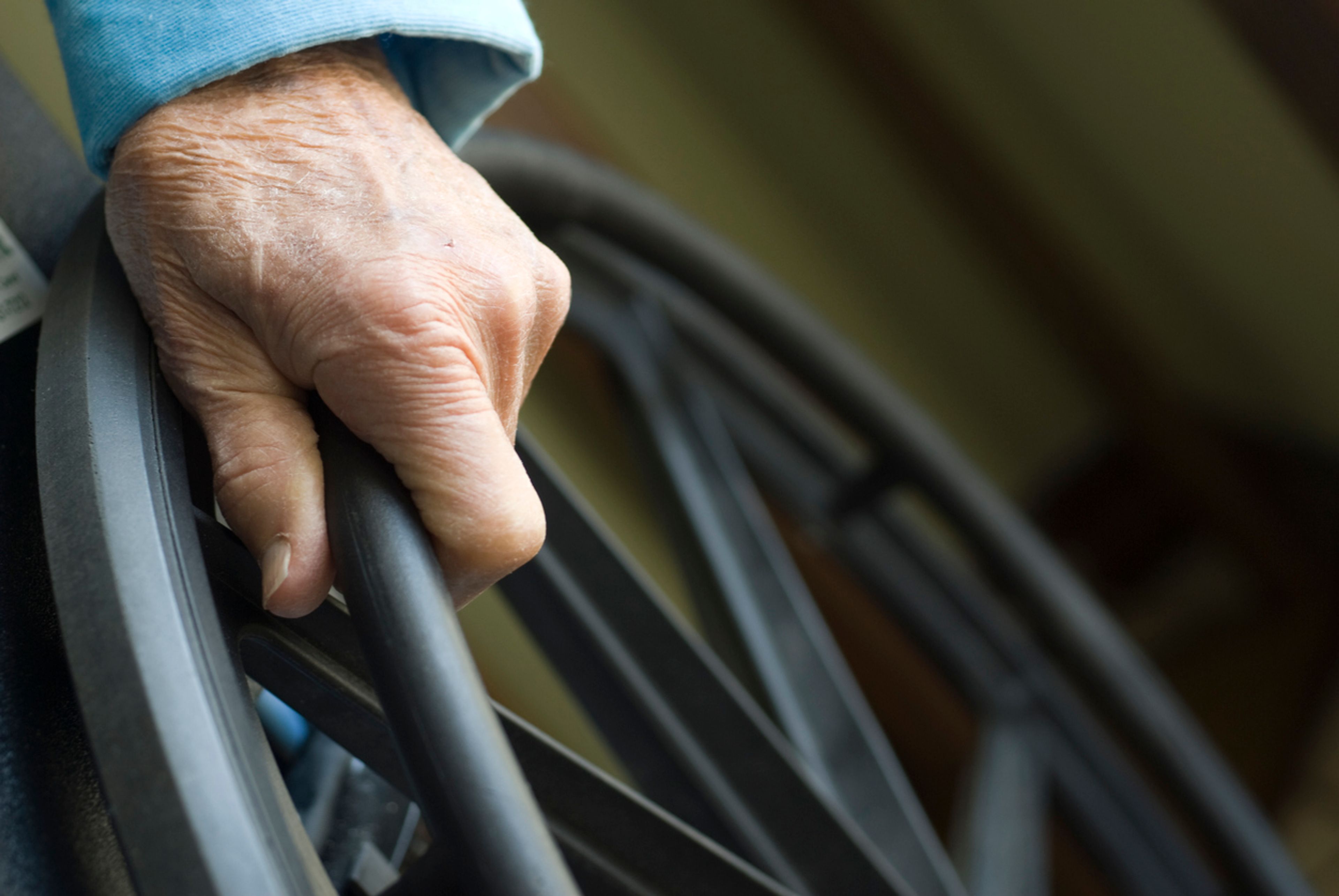 Closeup of a senior citizen's hand on a wheelchair.