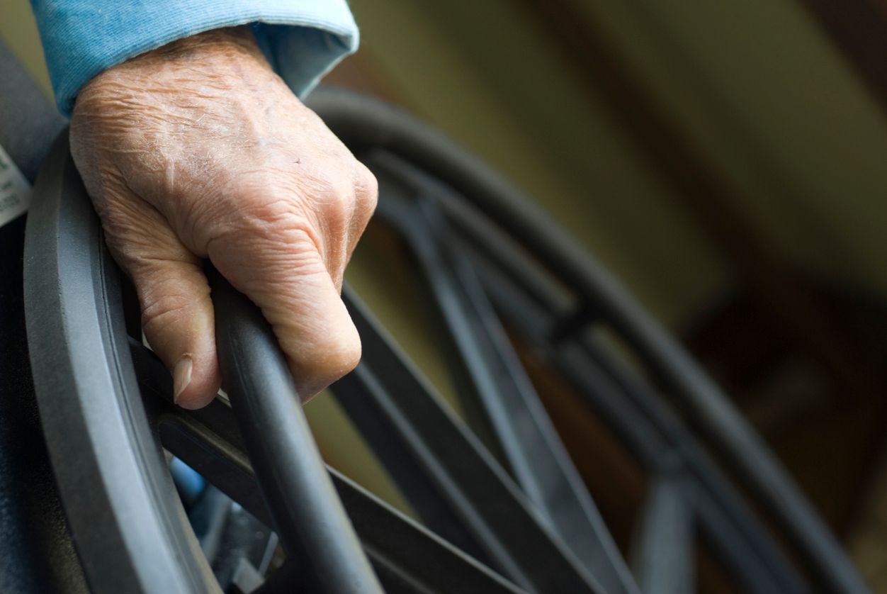 Closeup of a senior citizen's hand on a wheelchair.