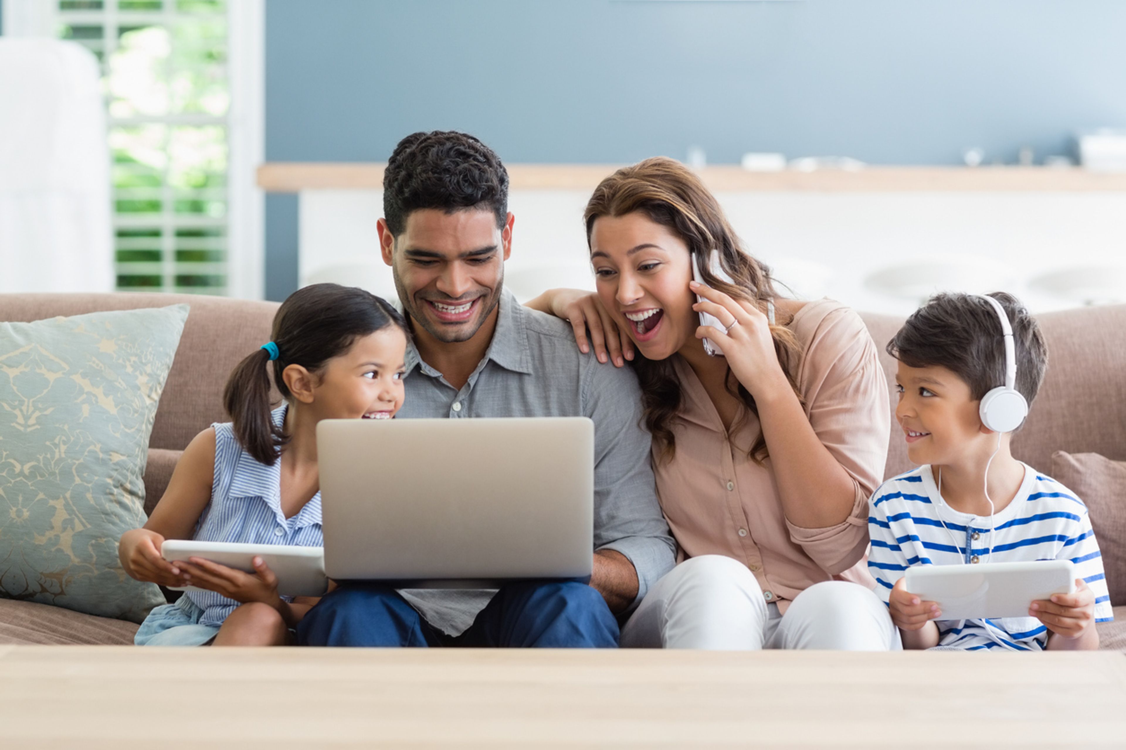 Parents looking up priority dates together on their laptop next to their two kids.