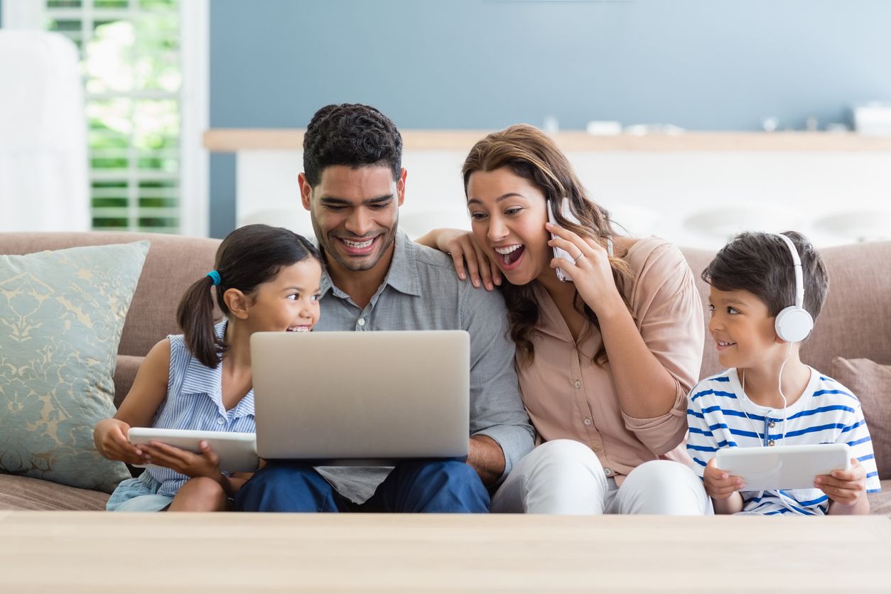 Parents looking up priority dates together on their laptop next to their two kids.