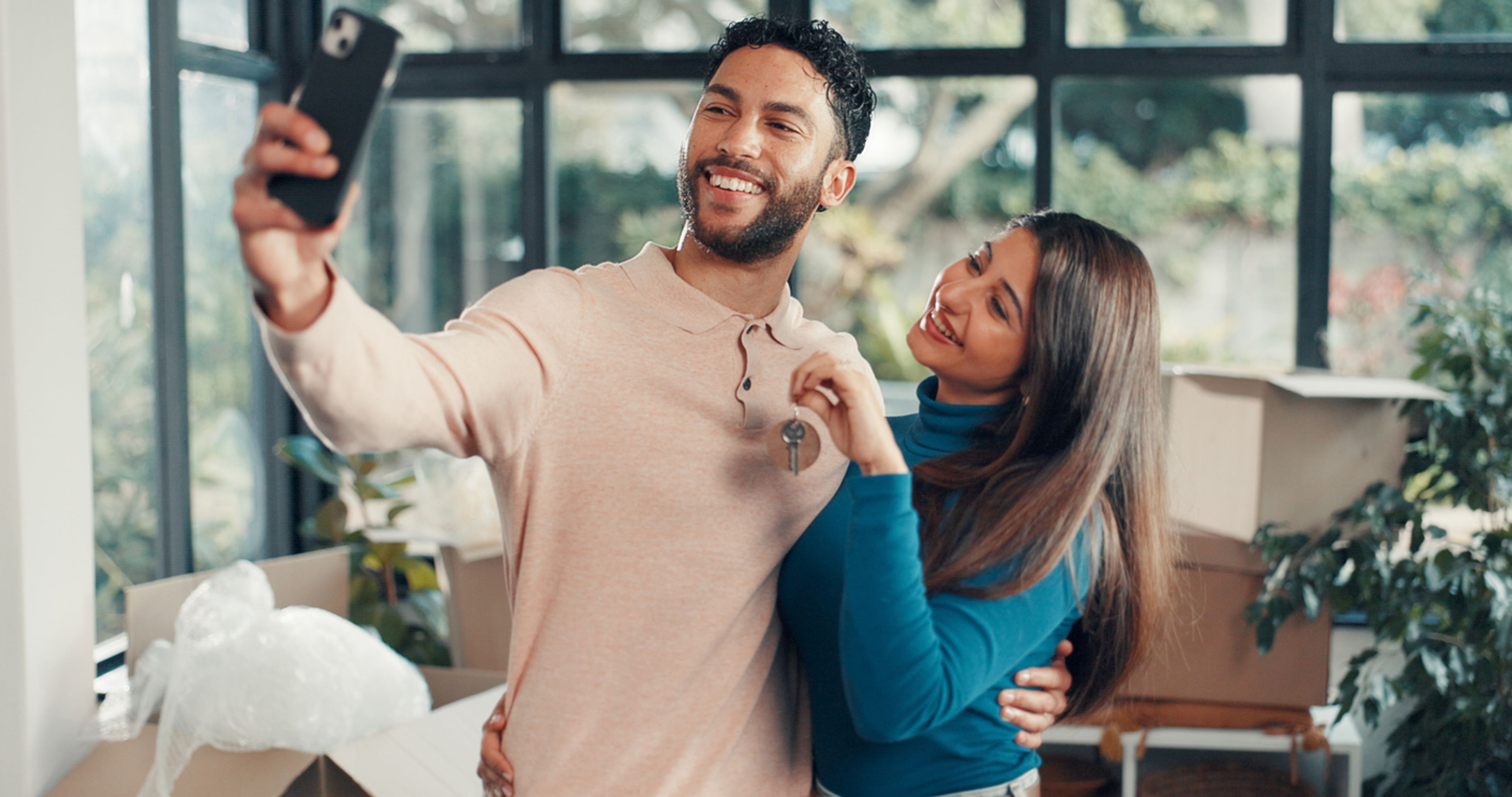 Couple taking a taking a selfie displaying the keys to their new home.