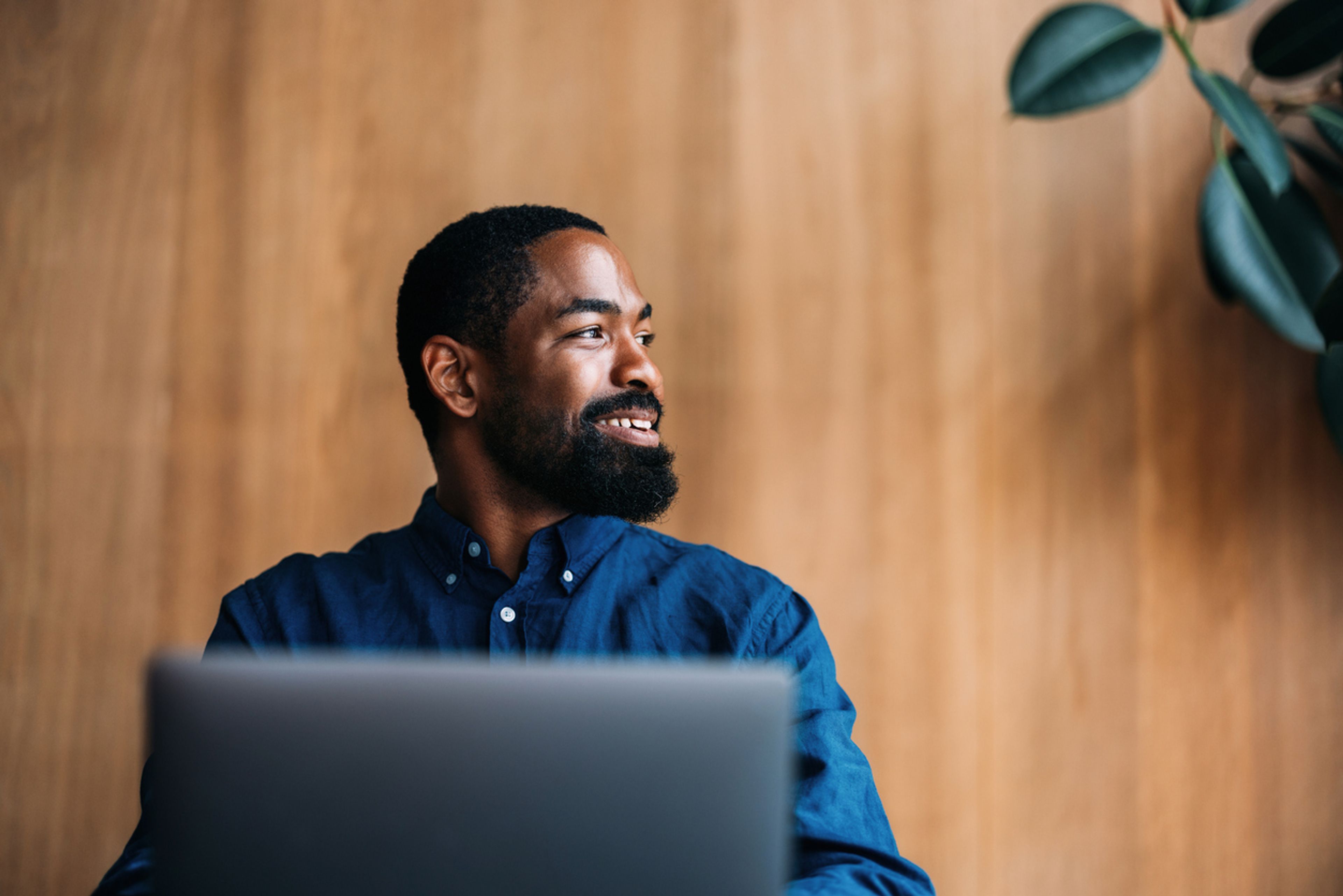 A confident professional man sits working on his laptop in a modern office space.