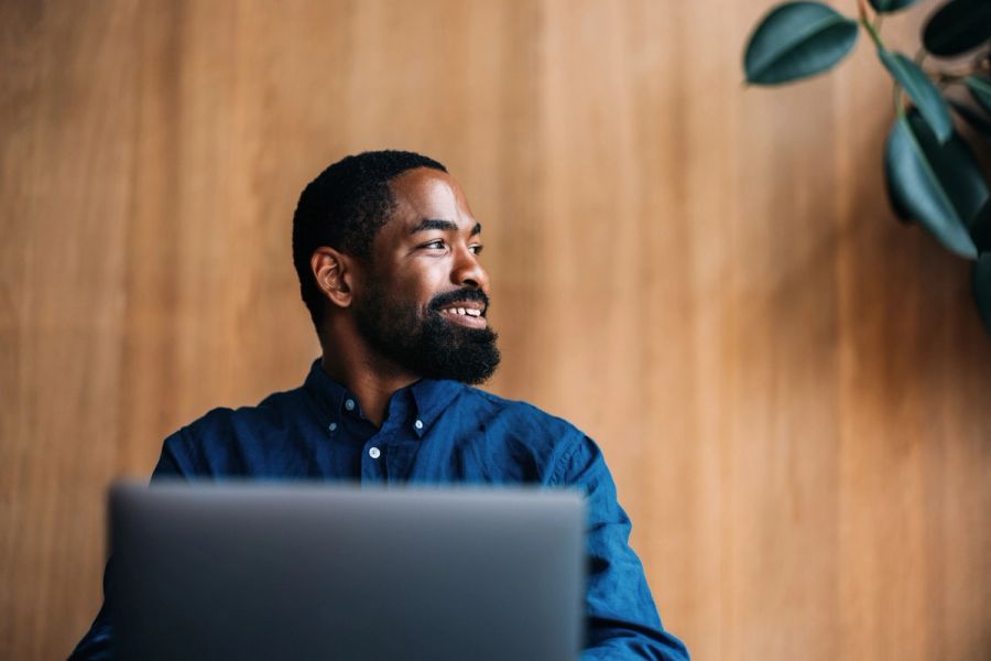 A confident professional man sits working on his laptop in a modern office space.