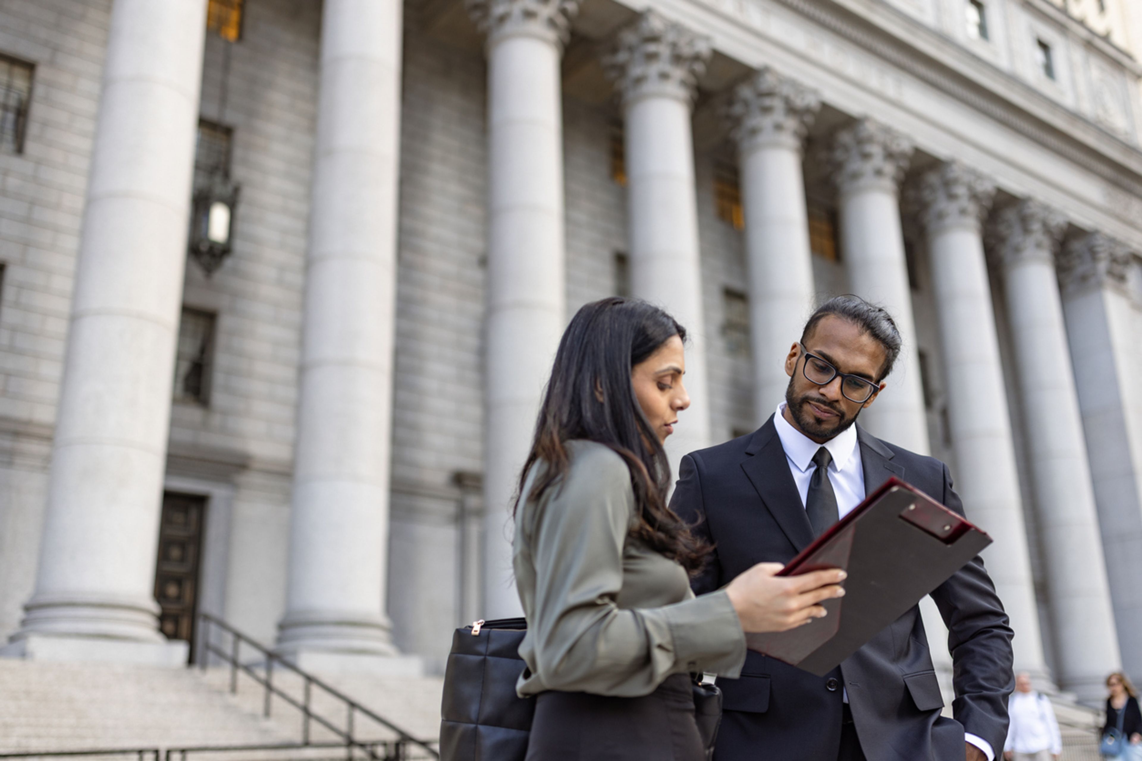An attorney and their client standing in front of the exterior of a courthouse.