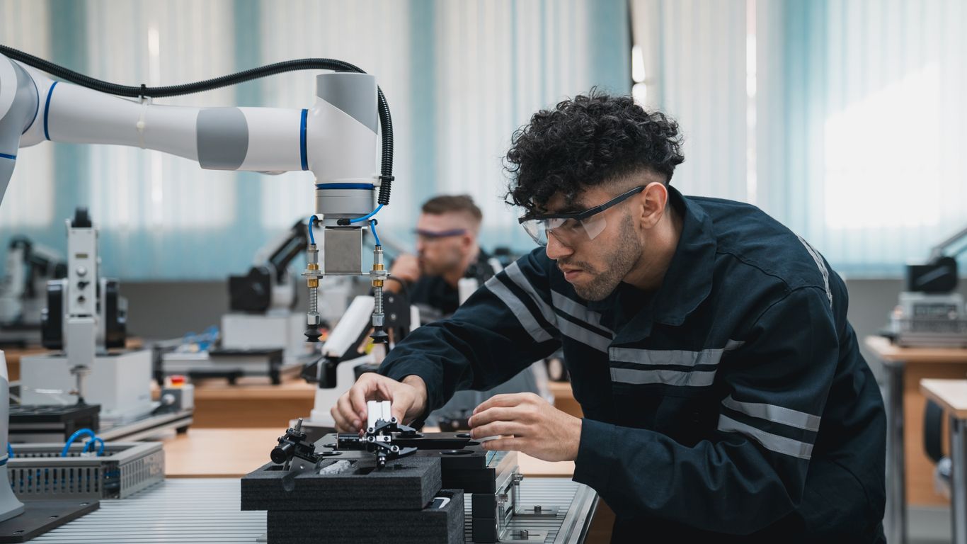 Student engineer assembling a robotic arm in a technology workshop.