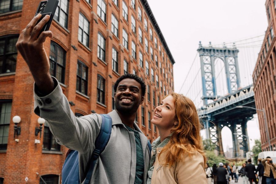 Tourists in the U.S. taking a selfie near the Brooklyn Bridge.