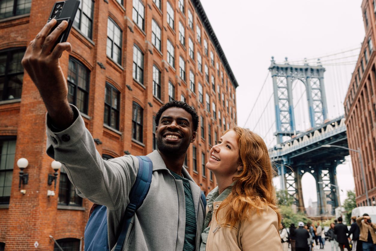 Tourists in the U.S. taking a selfie near the Brooklyn Bridge.