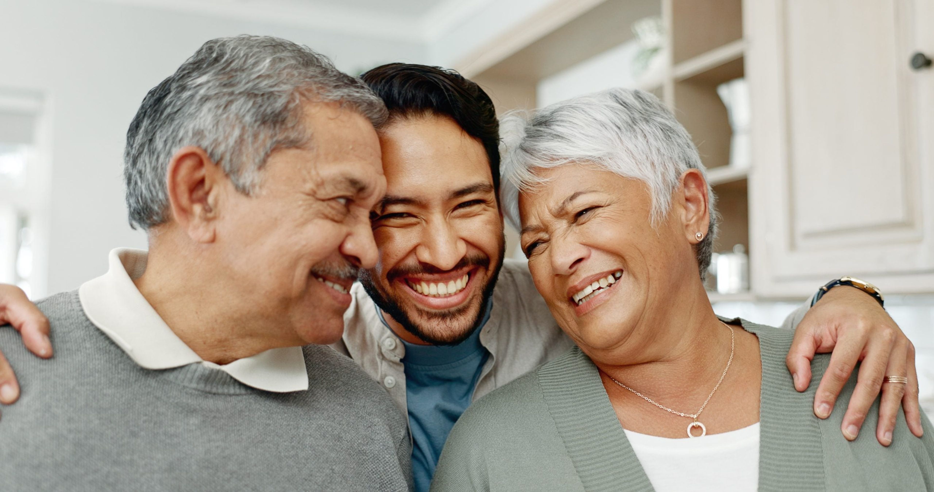 A closeup of a man hugging his two older parents, who received an IR-5 visa