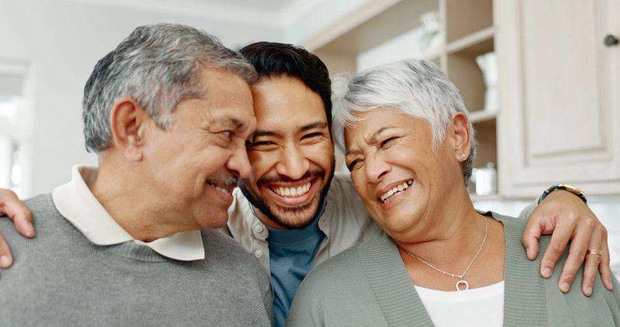 A closeup of a man hugging his two older parents, who received an IR-5 visa