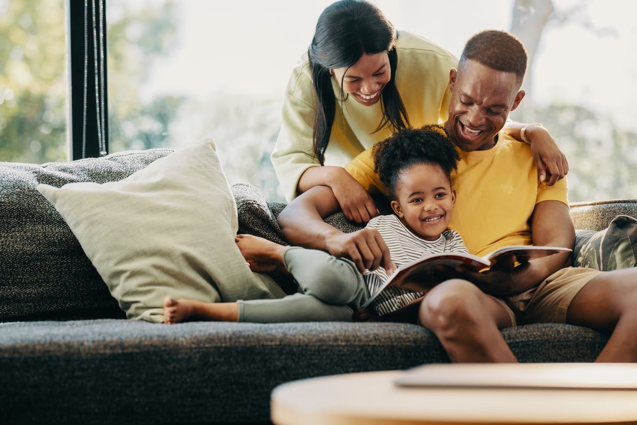 Happy little girl reading a story with her mother and father.