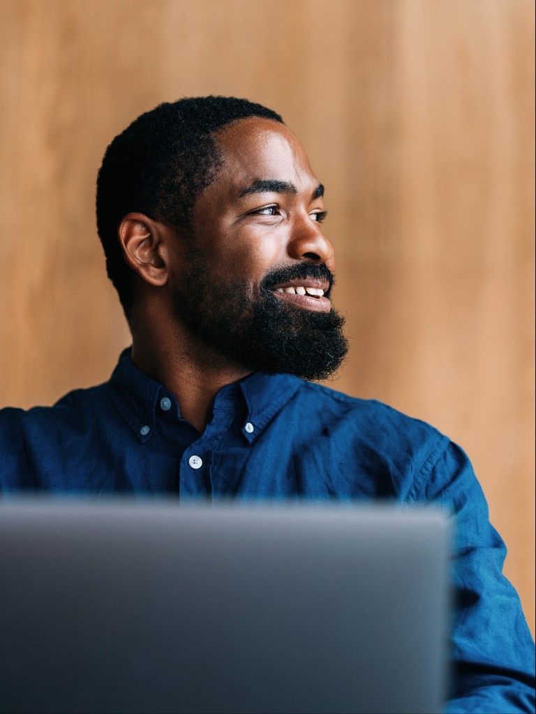 An engineer smiling while working at a laptop