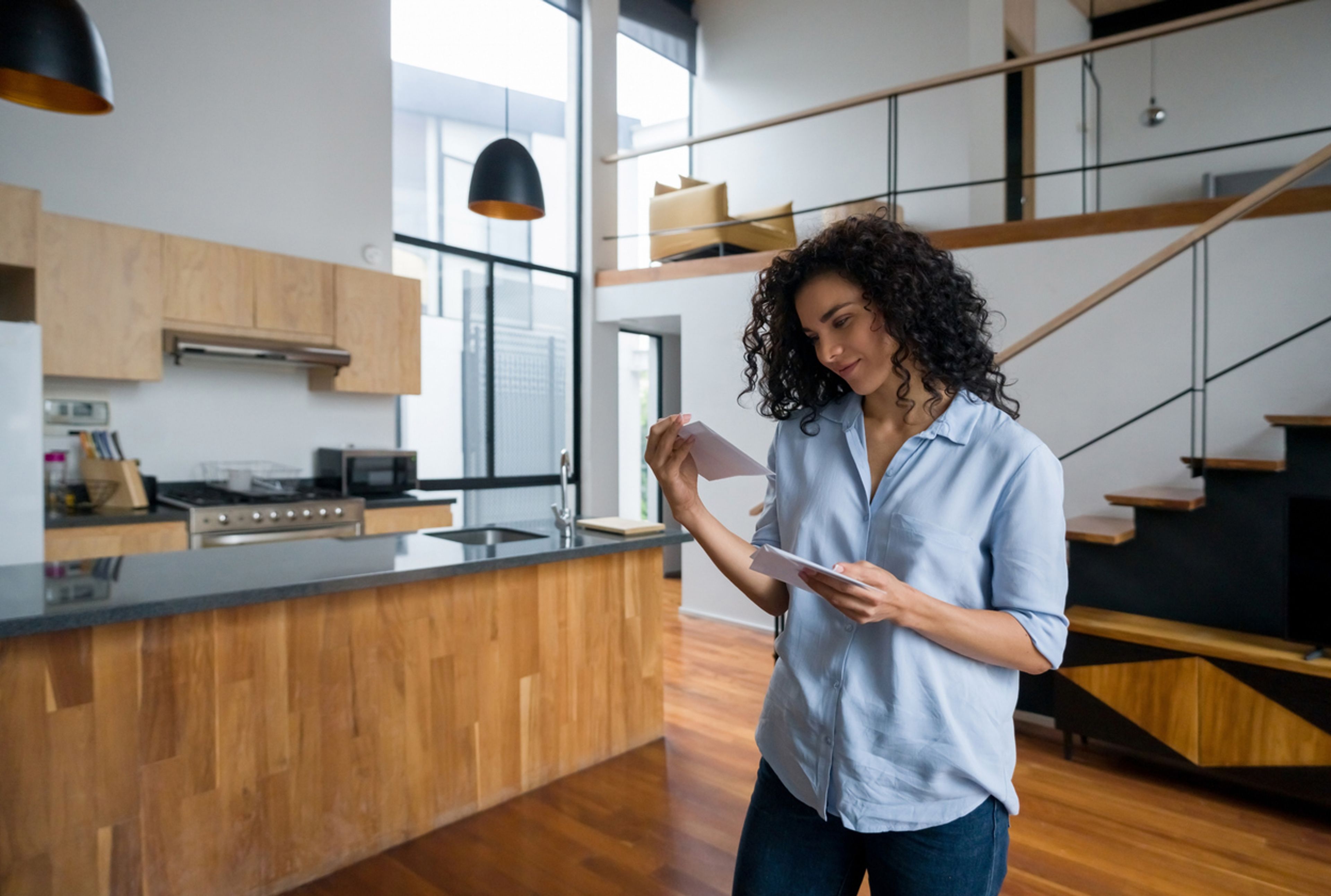 Woman holding an envelope in her kitchen.