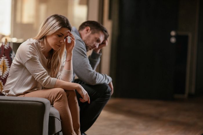 Concerned married couple sitting on a couch together.