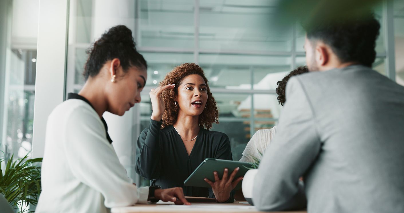 three people in meeting in office, one holding a tablet
