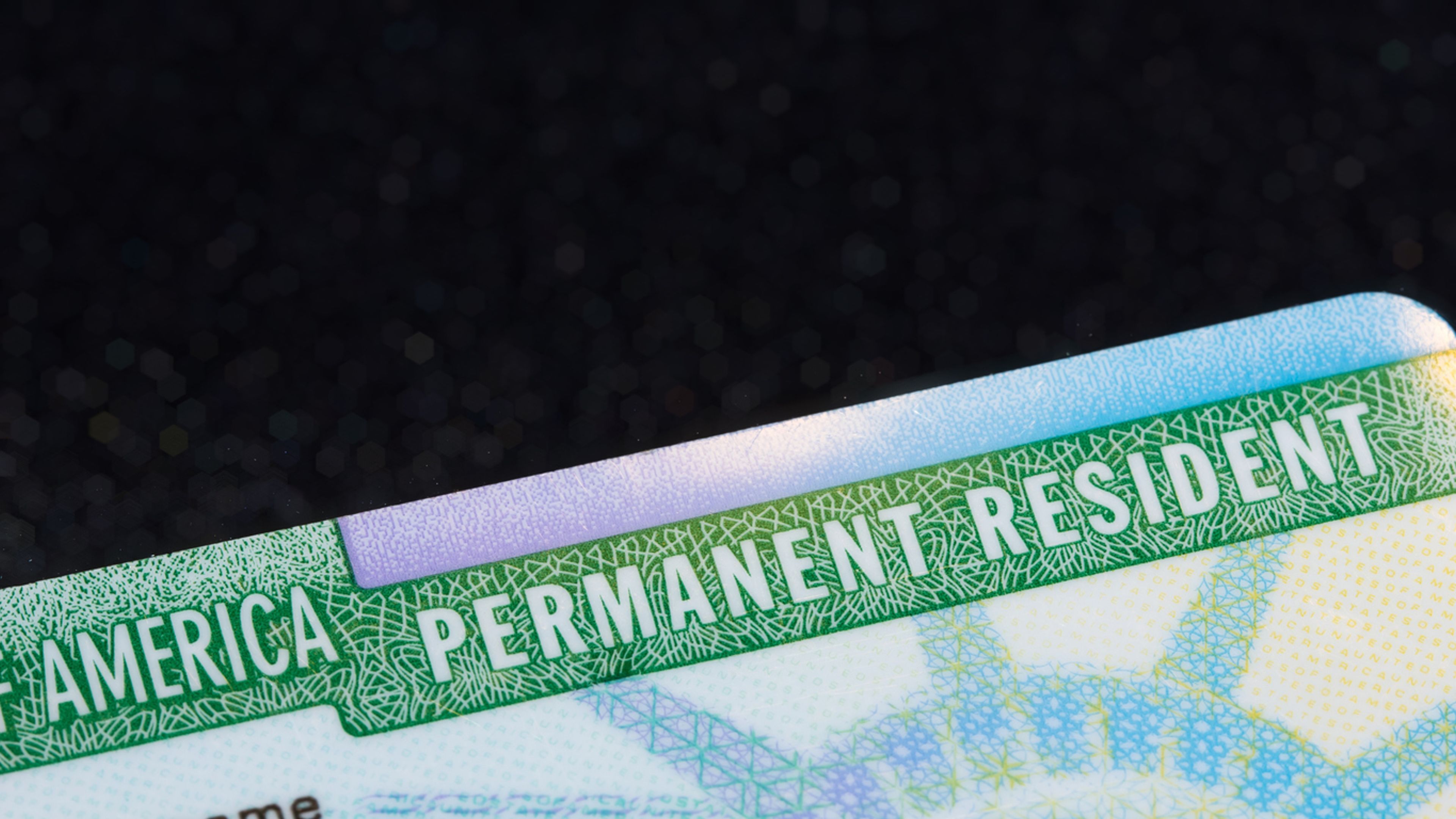 Closeup of a Green Card against a black background.