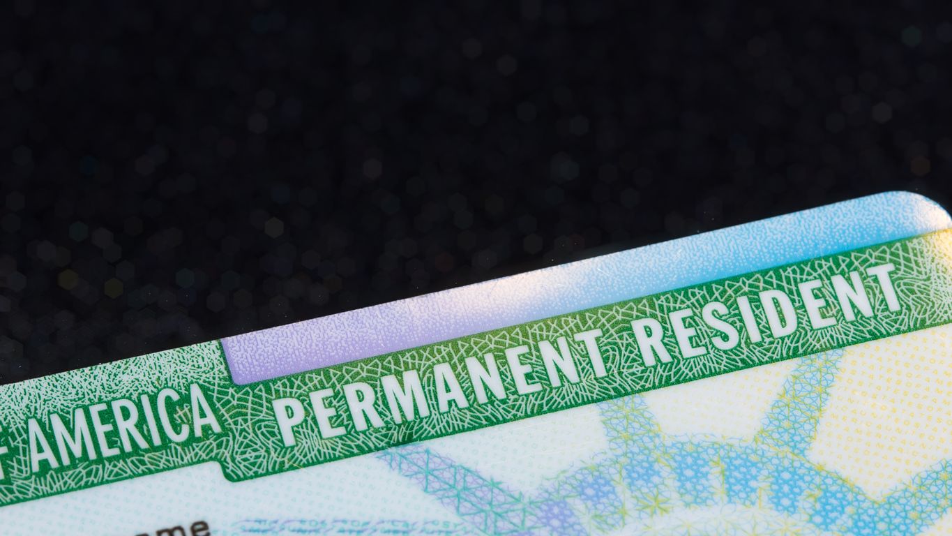 Closeup of a Green Card against a black background.