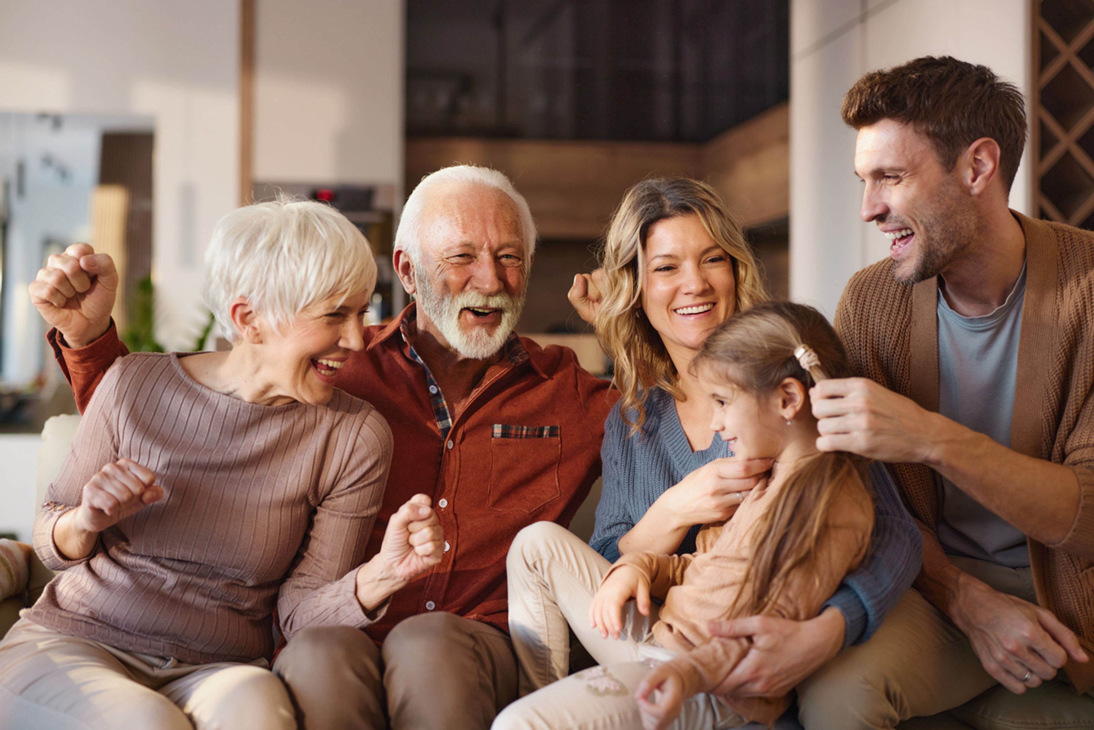 Cheerful multi-generation family laughing together in the living room.
