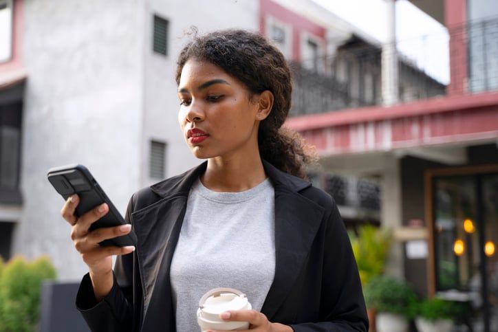 Business woman is outside and looking at her phone anxiously.
