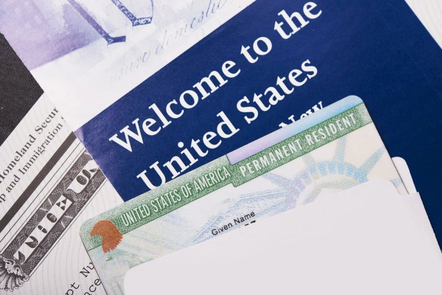 Closeup of a Green Card against a welcome packet.