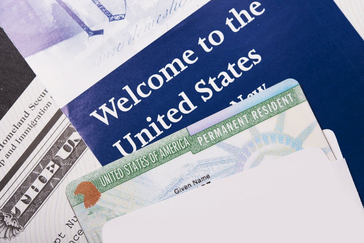 Closeup of a Green Card against a welcome packet.