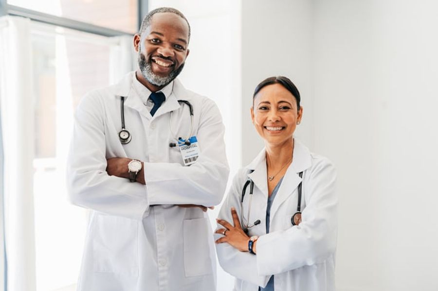 Two doctors stand side by side smiling.
