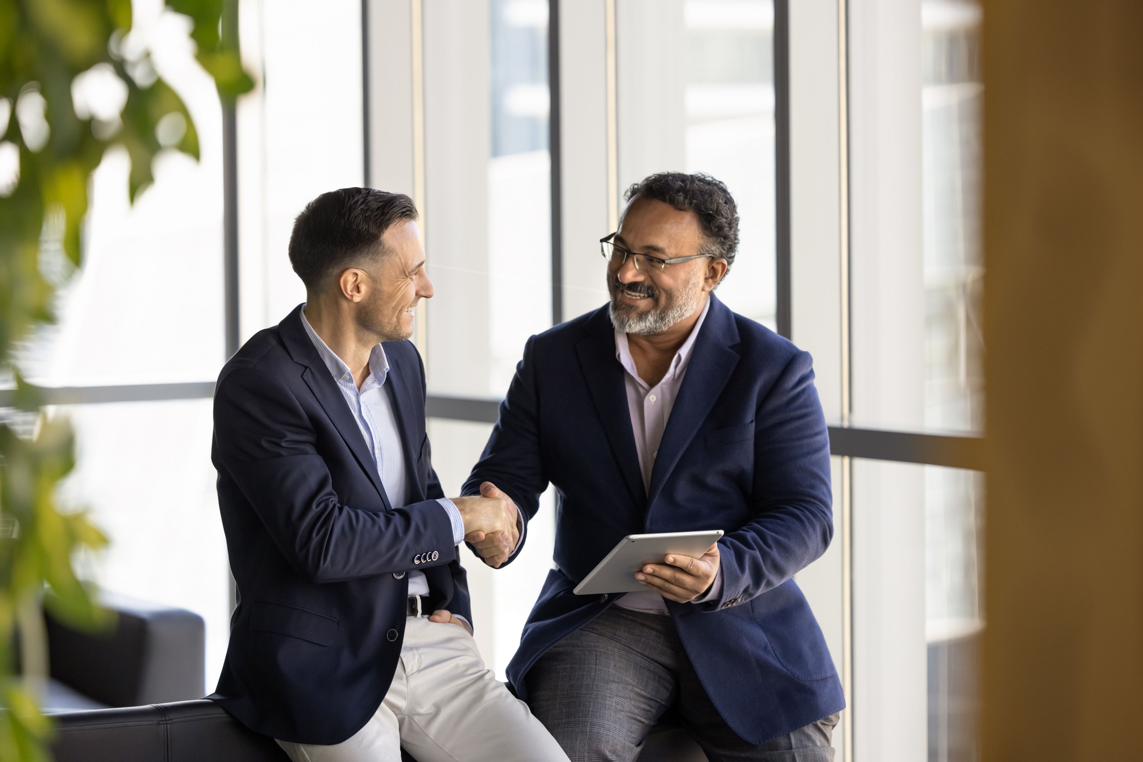 person holding tablet shaking hands with another person in an office