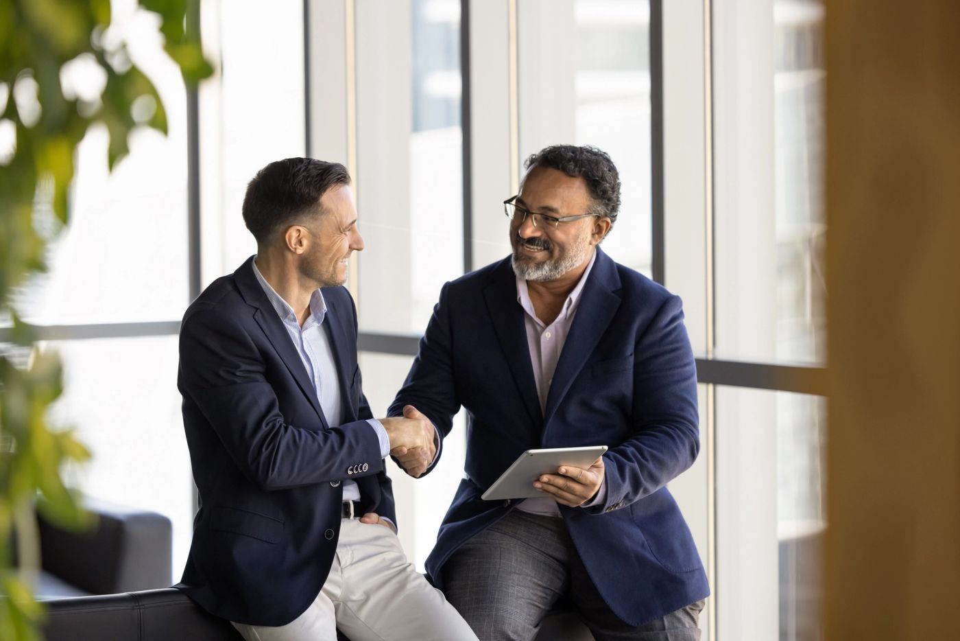person holding tablet shaking hands with another person in an office