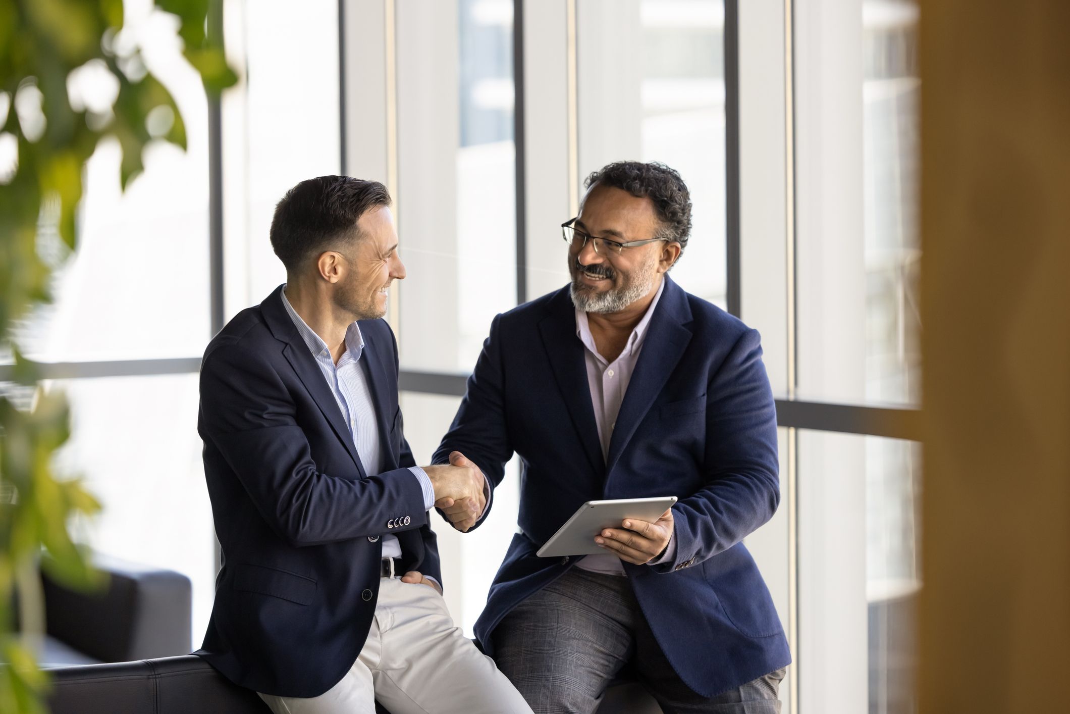 person holding tablet shaking hands with another person in an office