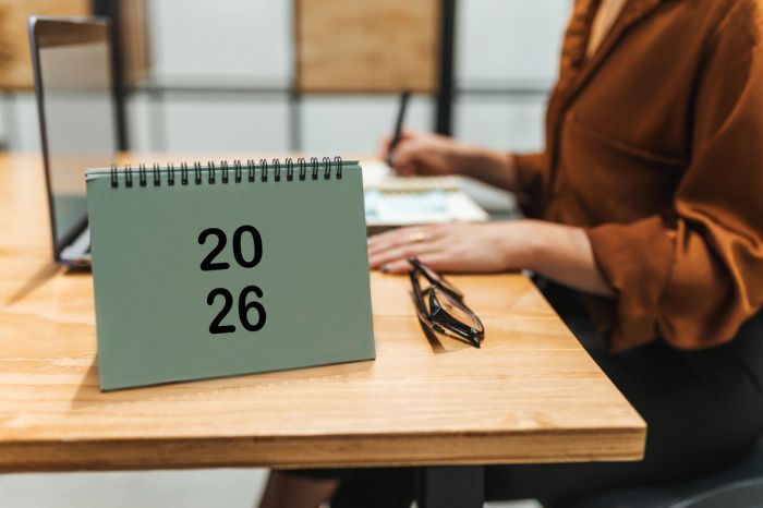 A professional working at an office desk beside a 2026 desk calendar.