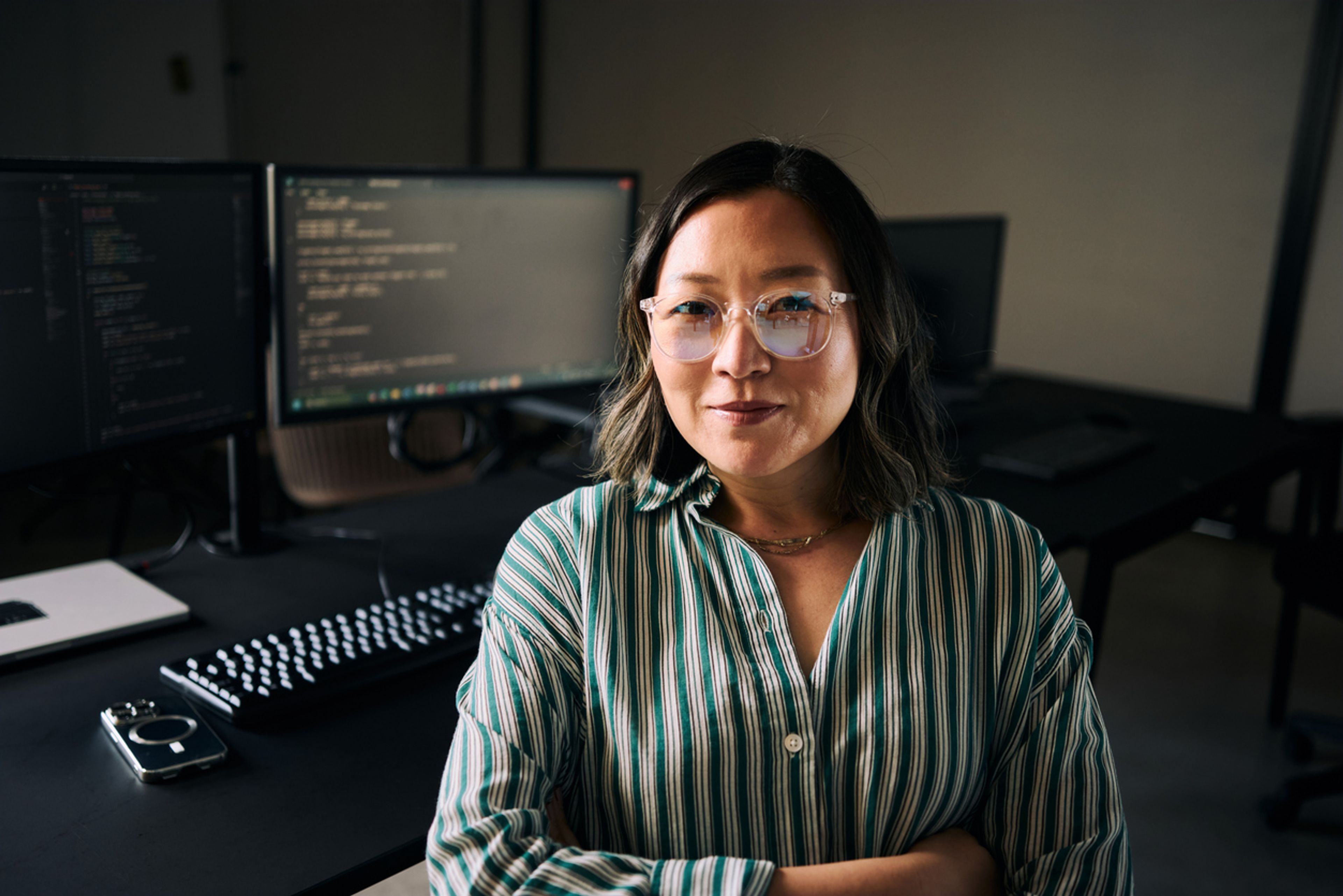 Software engineer sitting in front of monitors displaying her code.