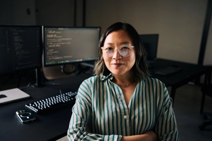 Software engineer sitting in front of monitors displaying her code.