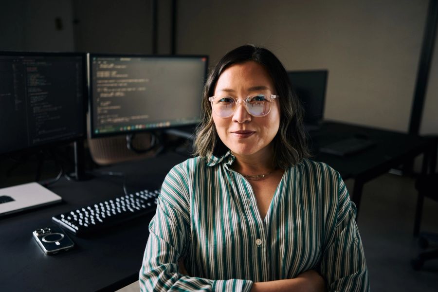 Software engineer sitting in front of monitors displaying her code.