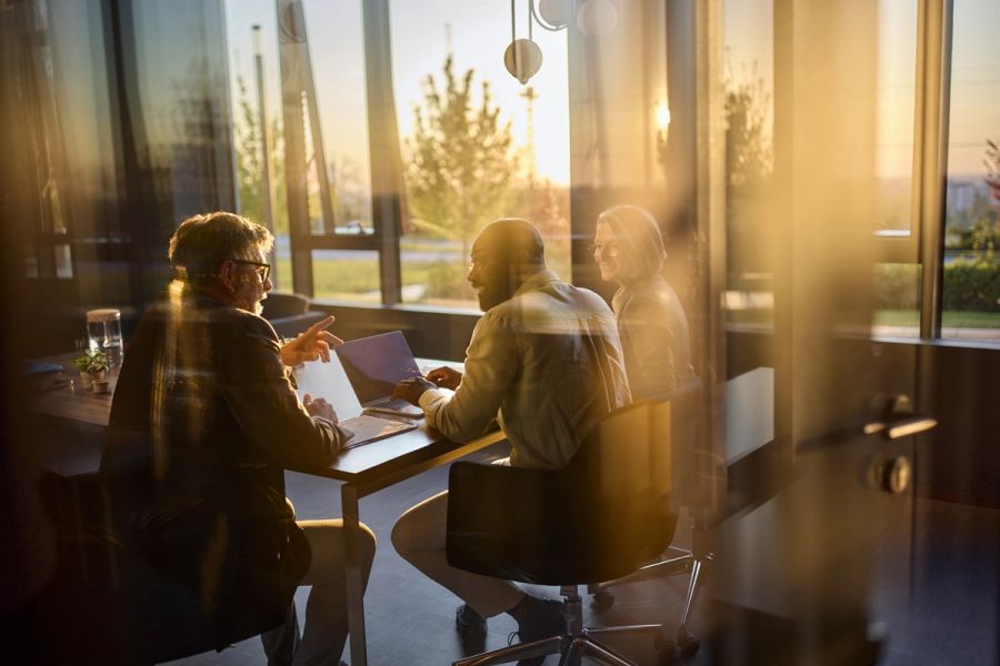 business professionals discussing work on a laptop during an evening meeting in a contemporary office setting