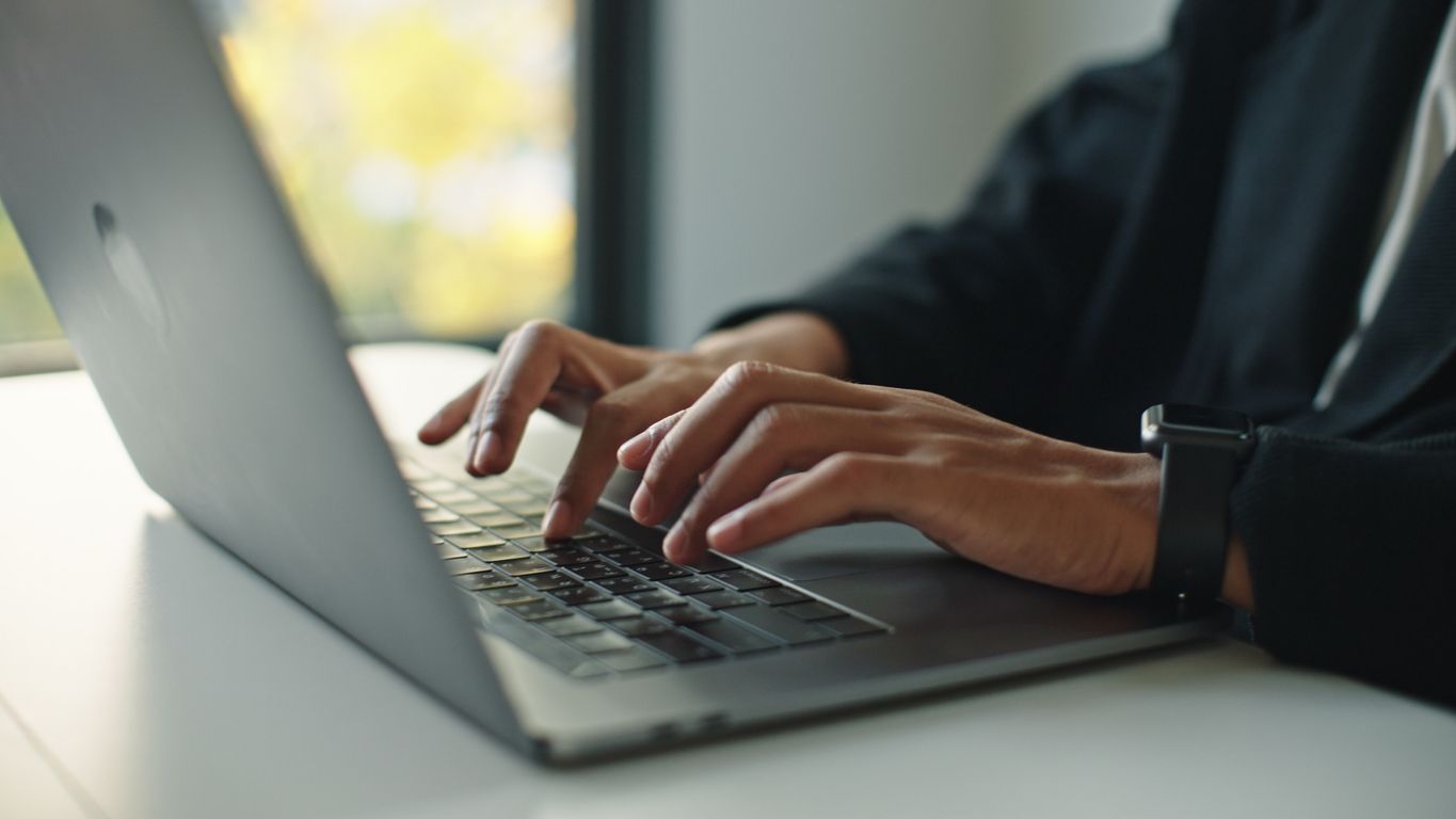 Closeup of hands typing on a laptop.