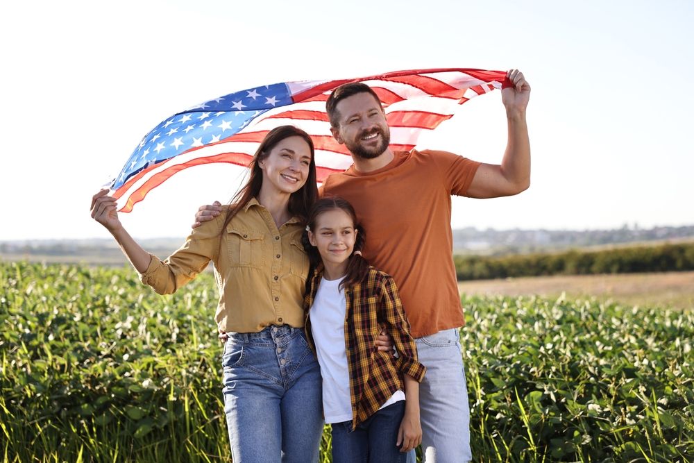 Mother and father with their daughter holding an American flag over their heads.