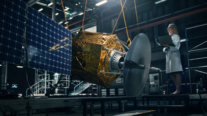 Industrial engineer working on model of satellite in lab.