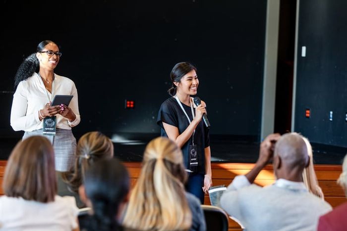 A sucessful business woman speaks through a microphone at a seminar.