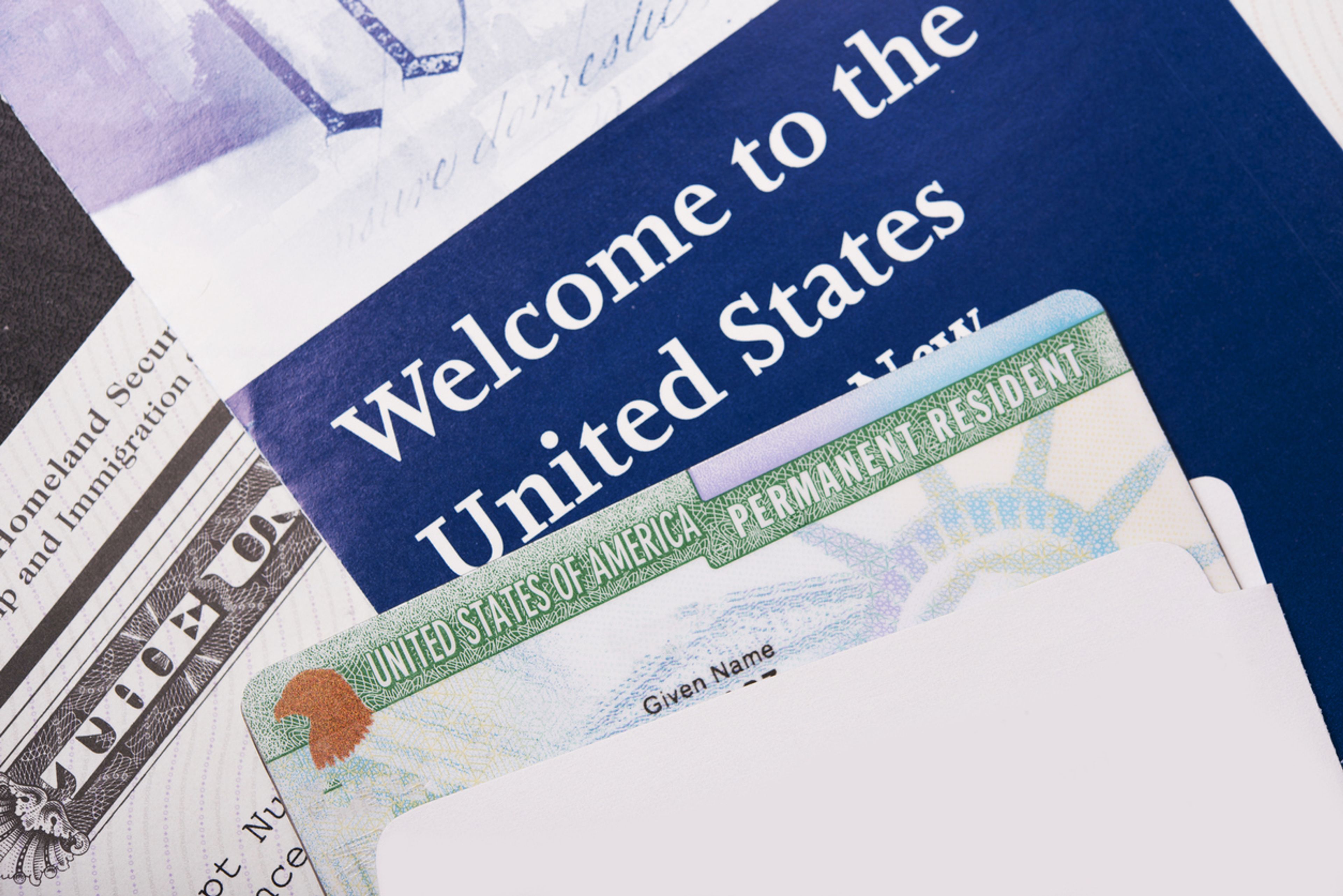 Closeup of a Green Card against a welcome packet.