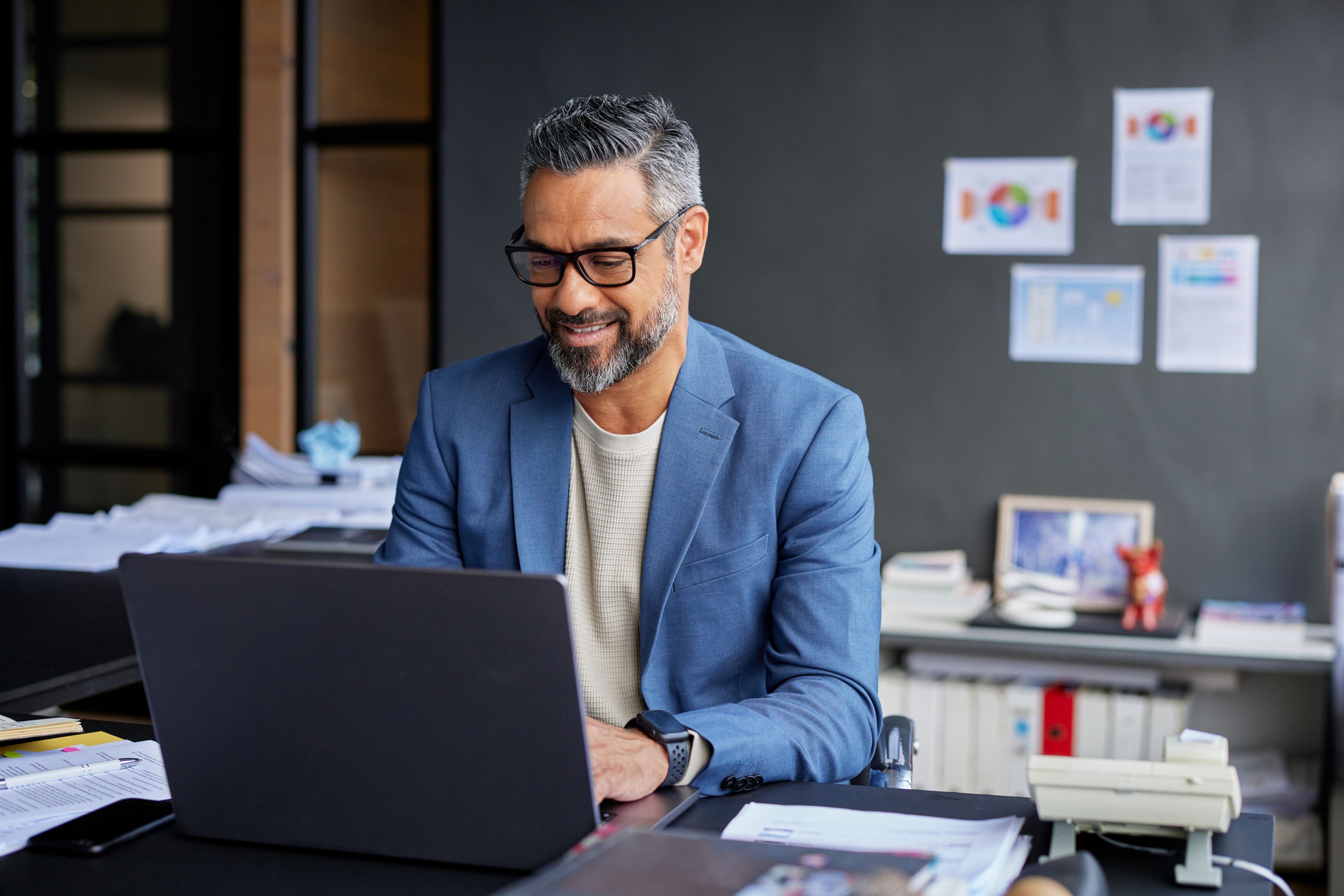 Business professional working on a laptop at a desk in an office.
