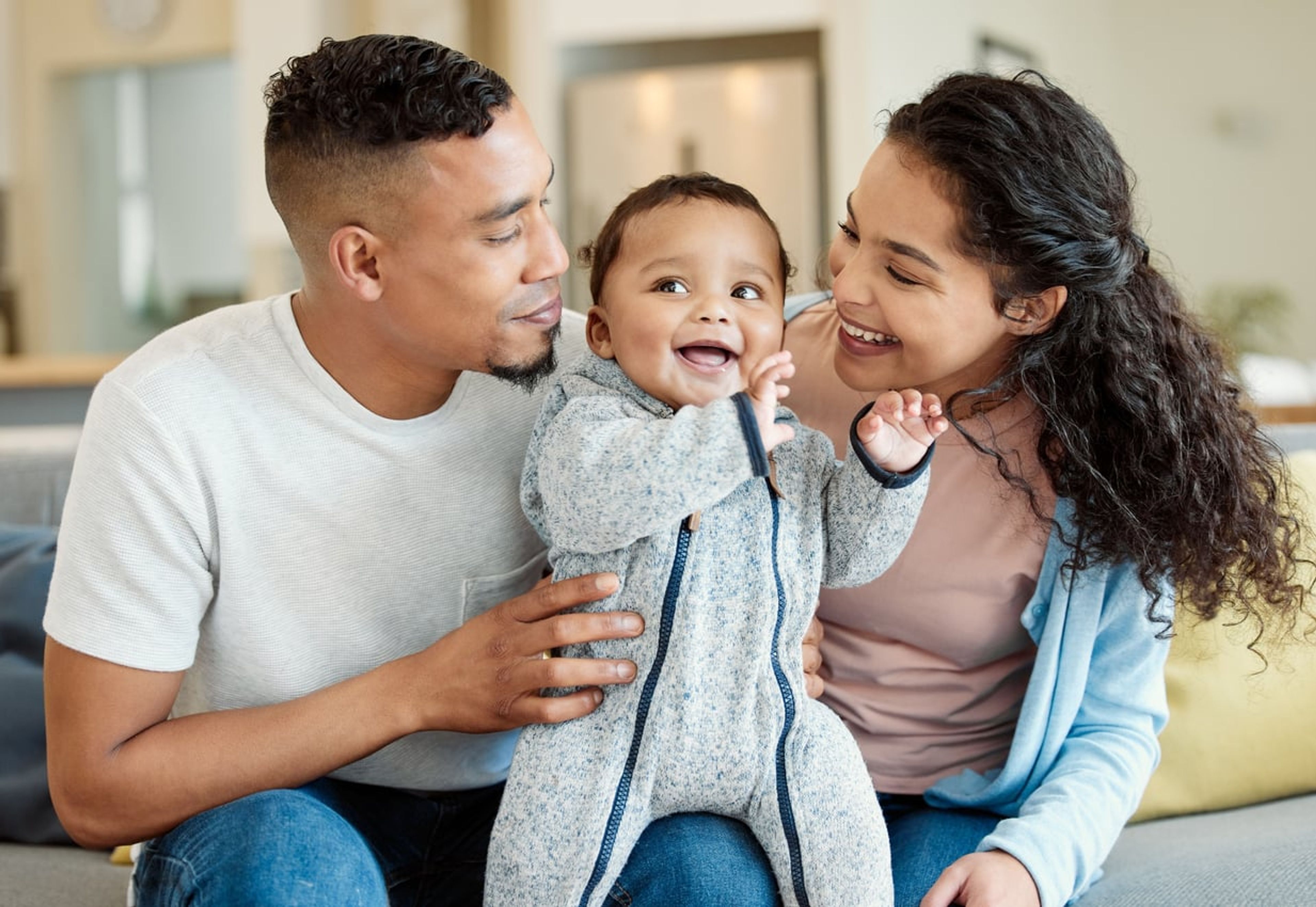 A young married couple smiling with their child.