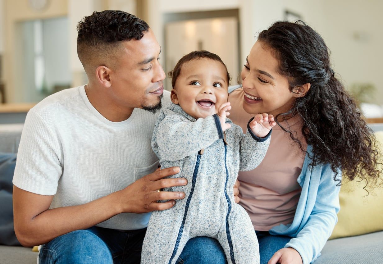 A young married couple smiling with their child.
