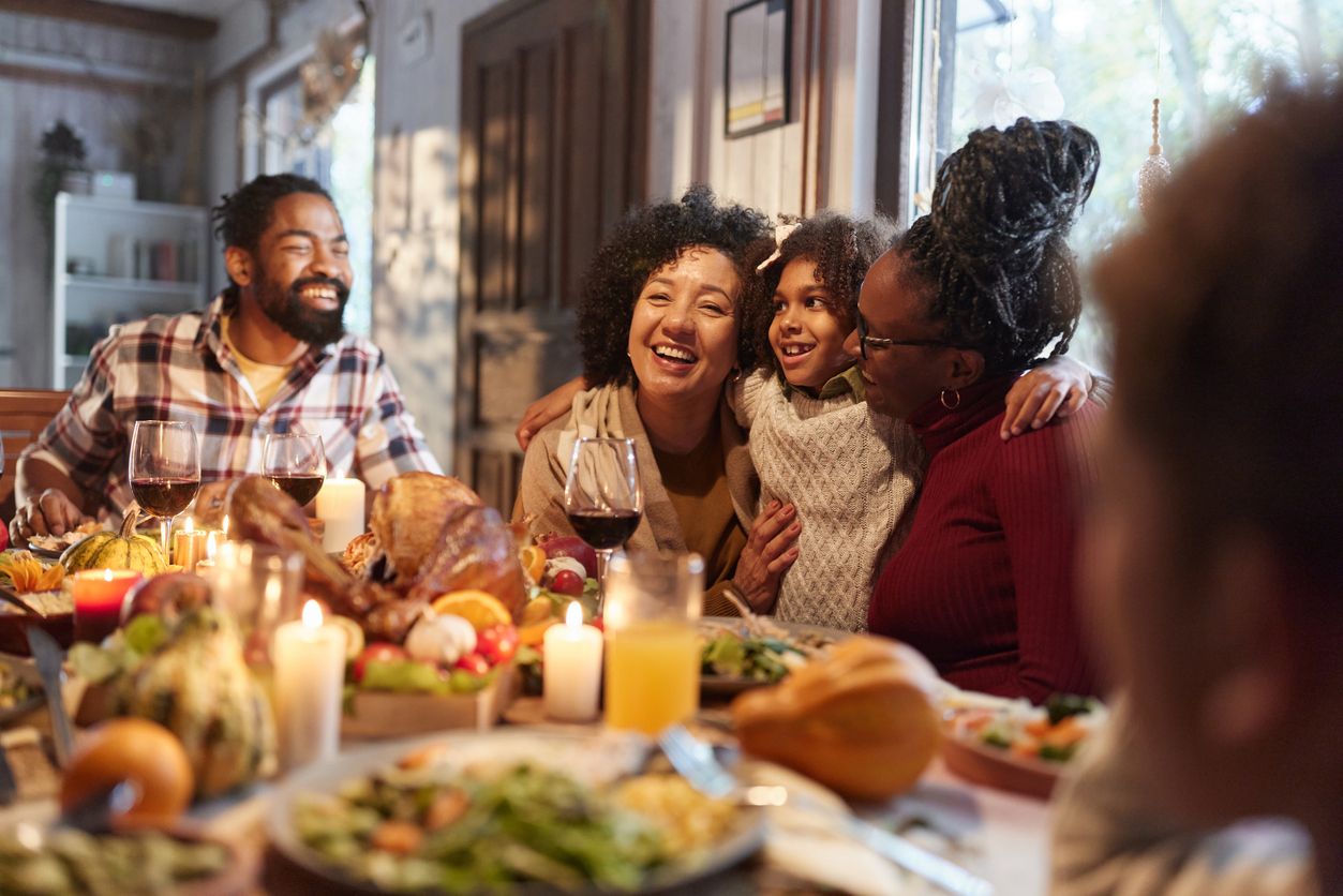 Big family sitting around dinner table smiling and laughing together.