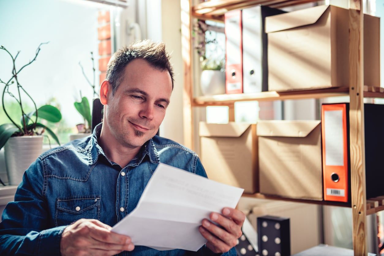 Man smiling while reading a notice in his office