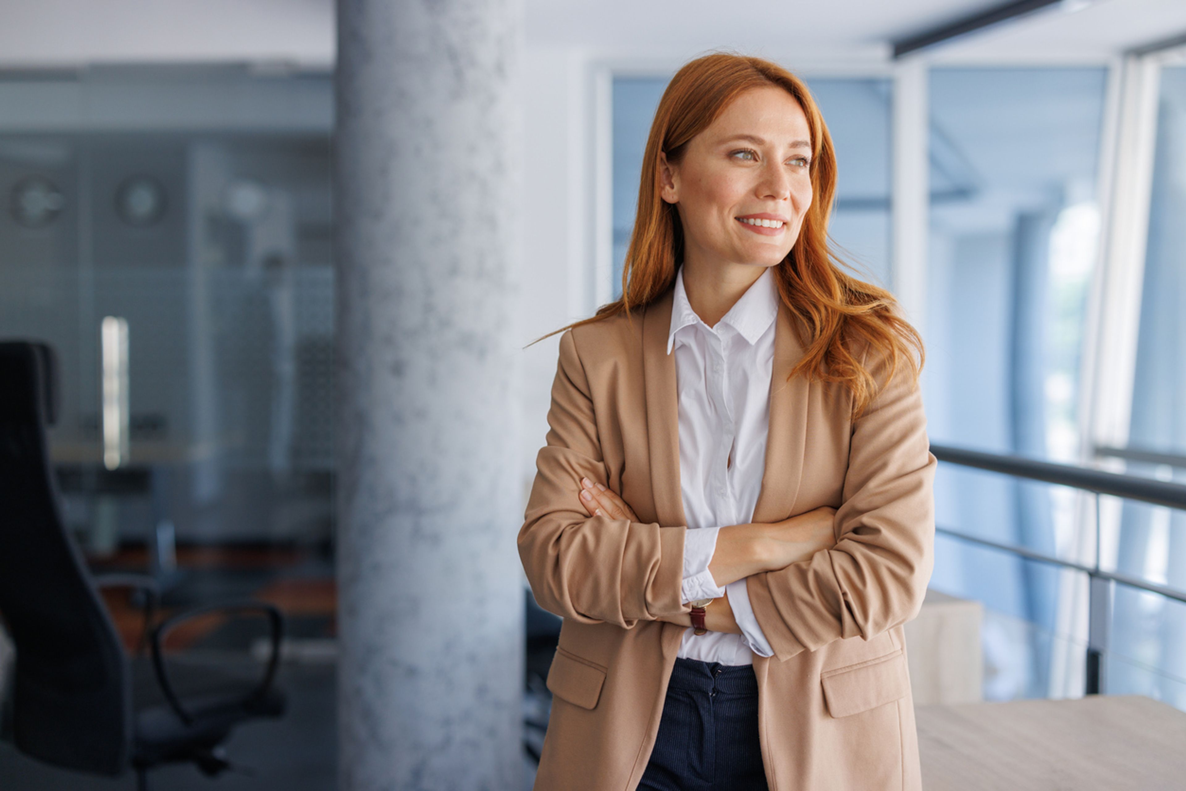 Portrait of an O-1 visa agent standing in a modern office with arms crossed.