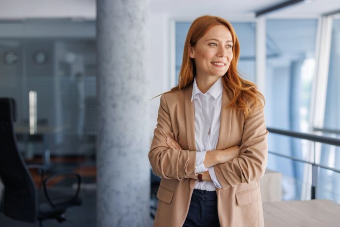 Portrait of an O-1 visa agent standing in a modern office with arms crossed.