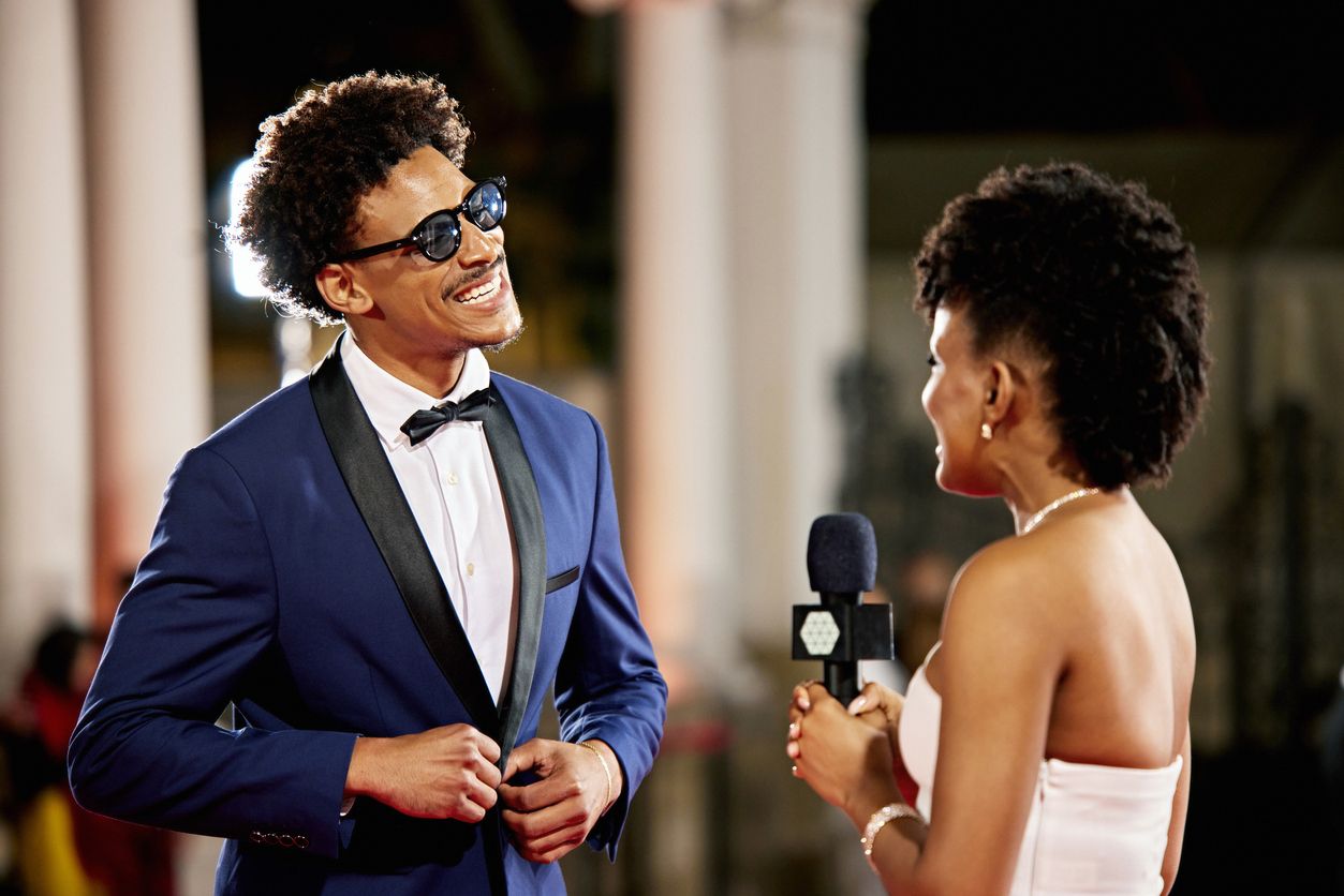 Celebrity giving an interview on the red carpet at an event.