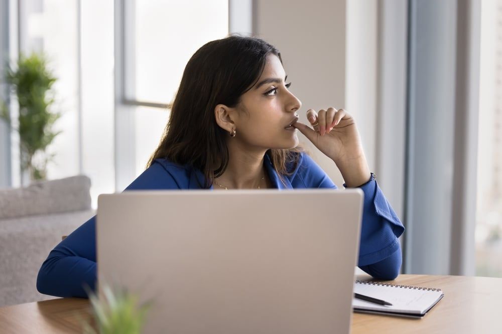 Worker in a startup office with her laptop with a serious expression on her face.