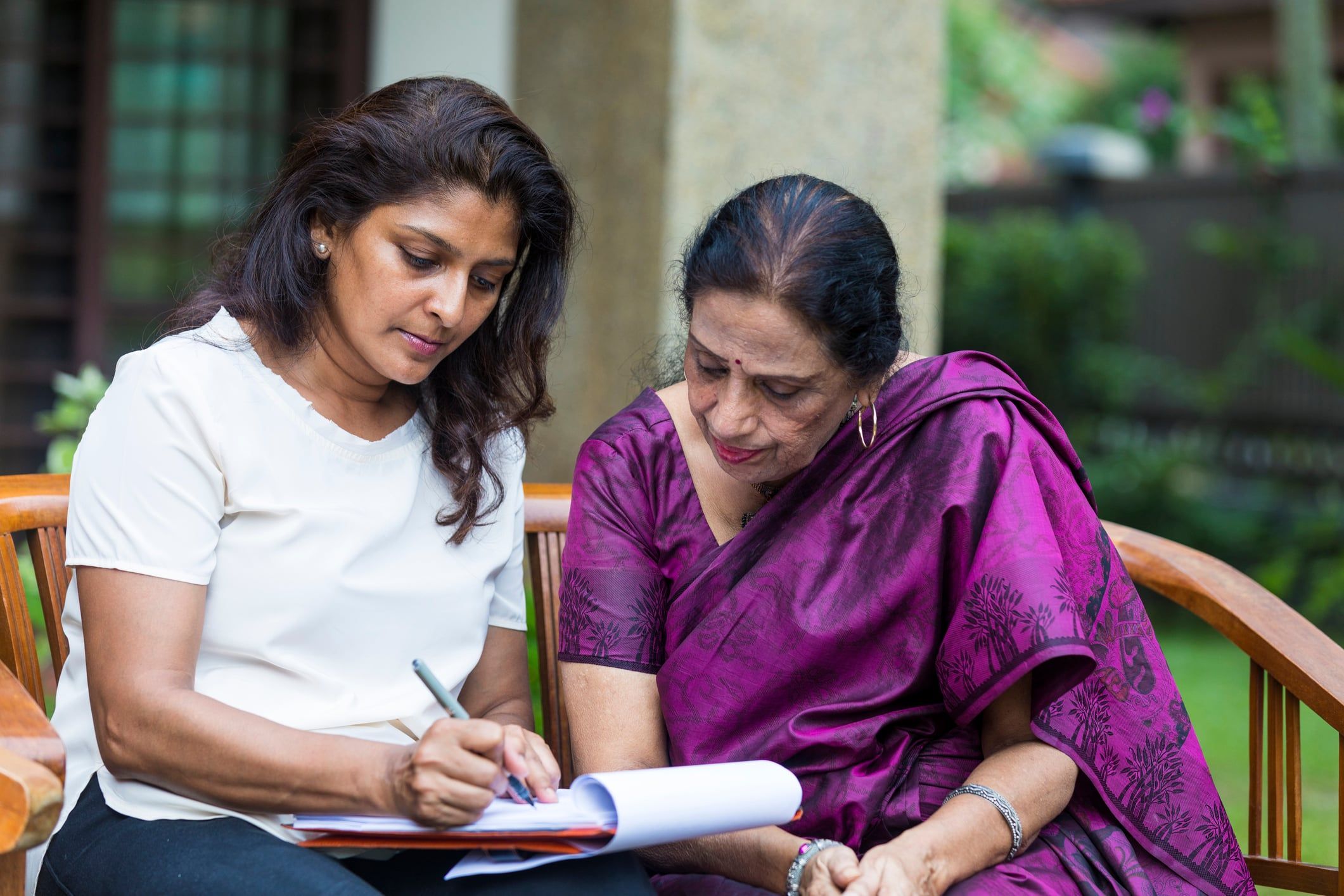 A seated woman and her mother complete the paperwork for a B-1/B-2 visa application.