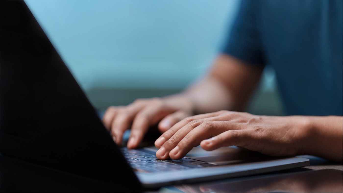 Close-up of hands typing on a laptop
