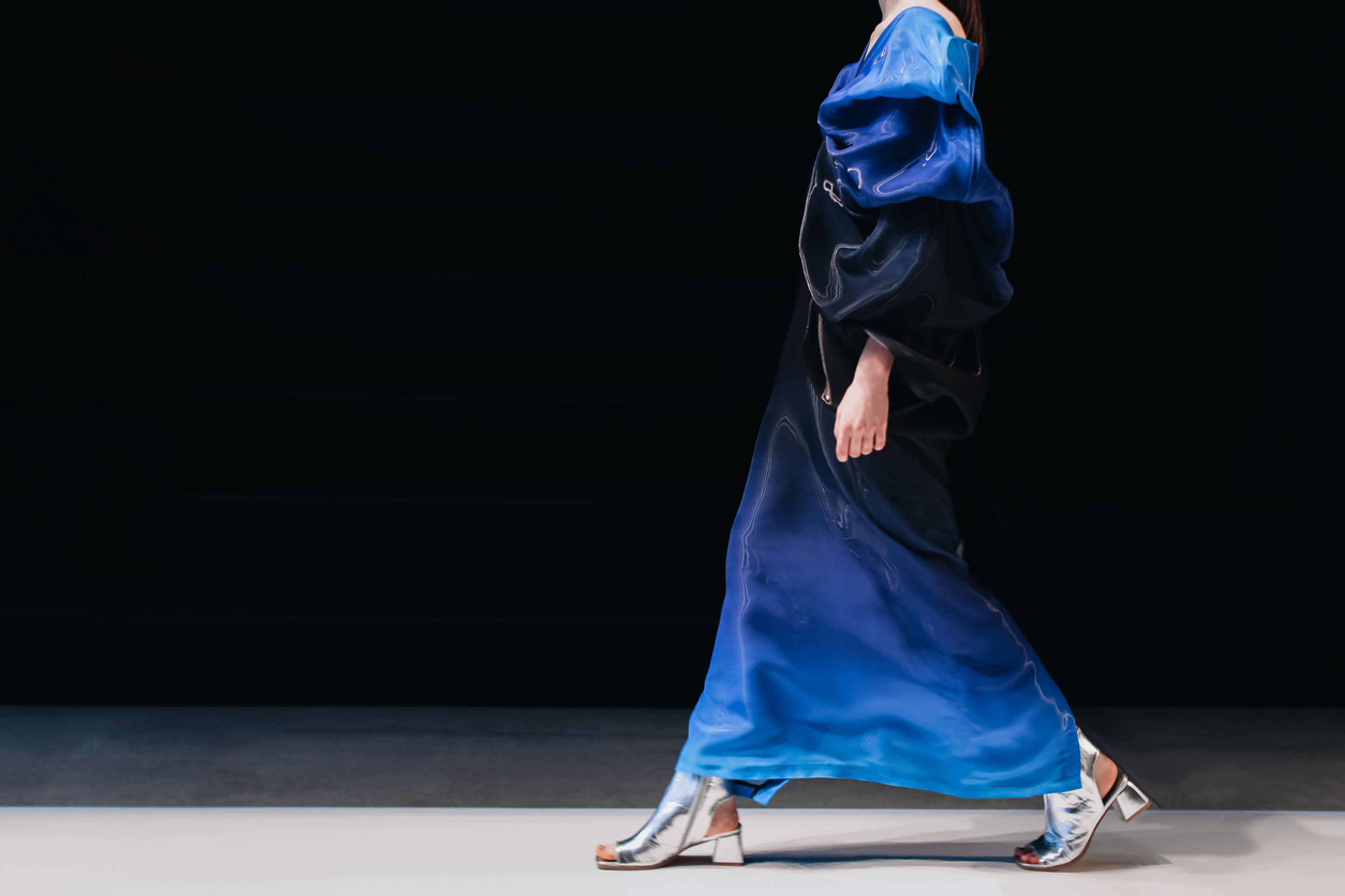 Fashion model on a walking the runway in a blue designer dress.